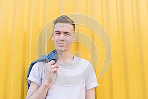 Happy young man in a white T-shirt on the background of a yellow wall