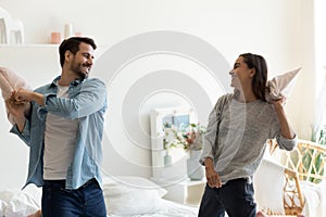 Happy young man and woman playing pillow fight at home