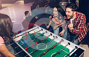 Happy young man and woman playing together in room. Intense game. Winning and loosing. Opponents at table soccer.