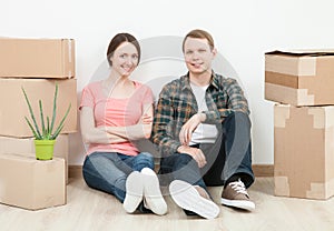 Happy young man and woman sitting near cardboard boxes