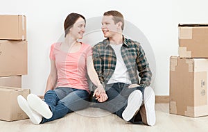 Happy young man and woman sitting near cardboard boxes