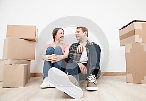 Happy young man and woman sitting near cardboard boxes