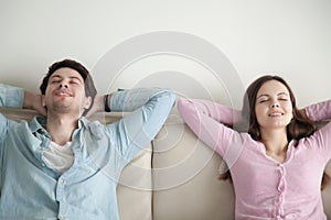 Happy young man and woman sitting relaxing with eyes closed
