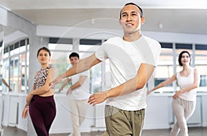 Happy young man and woman in sports clothes performing rock and roll dance in dancing room during training