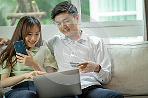 Happy young man and woman using laptop together, couple shopping or chatting online, using internet banking services