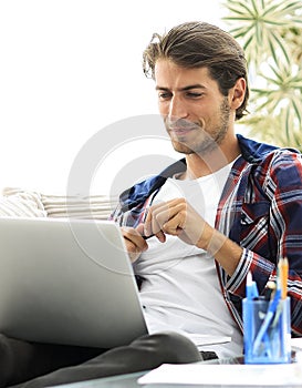 Happy young man working with laptop from home.