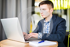 Happy young man works on his laptop to get all his business done early in the morning with his cup of coffee