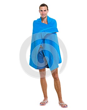 Happy young man wrapped in beach towel
