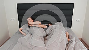 Happy young married couple sleeping together in bed. Woman and man in love are lying in bed and hugging. Relationship concept