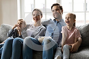 Happy young married couple watching tv with children.
