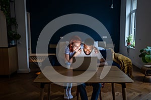 Happy young married multiracial couple using laptop together at home, planning summer vacation