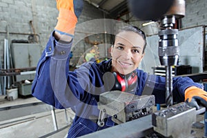 happy young mechanic apprentice working on milling machine