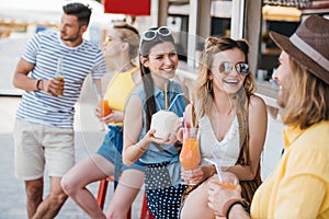 happy young men and women drinking summer cocktails