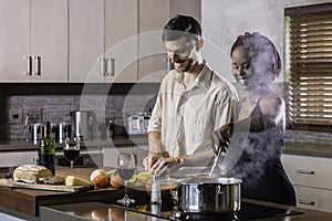 Happy young mixed race couple cooking dinner in kitchen