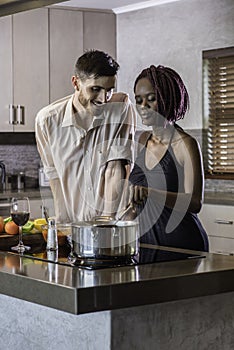 Happy young mixed race couple cooking dinner in kitchen