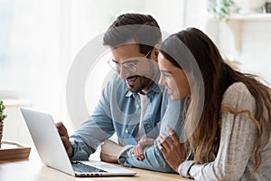 Happy young mixed race couple watching funny videos on computer.