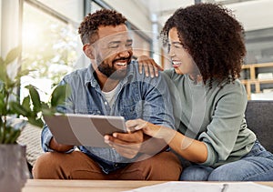 Happy young mixed race couple smiling while using a digital tablet together at home. Cheerful hispanic boyfriend and