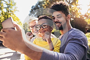 Happy young mixed race couple spending time with their daughter using smart phone