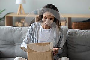 Happy young mixed race woman unpacking parcel.