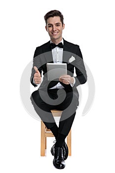 Happy young model holding tab and making thumbs up sign