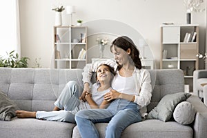Happy young mom and cute little daughter resting on couch