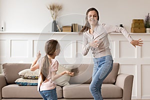 Happy young mom have fun dancing with preschooler daughter