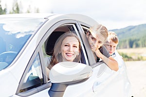 Happy young mom and her children sitting in a car