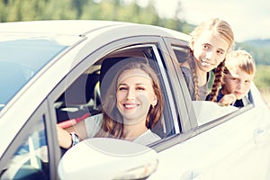 Happy young mom and her children sitting in a car