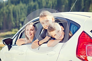 Happy young mom and her children sitting in a car