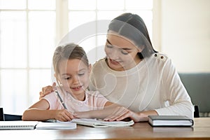 Happy young mom and little daughter do homework