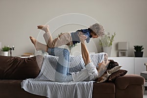 Happy mom and little son playing airplane in living room