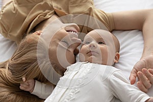 Happy young mom and newborn baby cuddle in bedroom