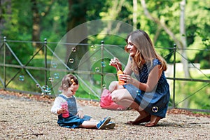 Happy young mother and adorable toddler girl walking through sum