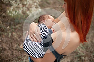 Happy young mother breastfeed newborn baby on walk.