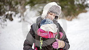 Happy young mother carrying her baby in a carrier