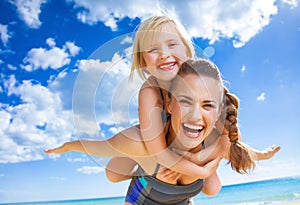 Happy young mother and child on beach having fun time