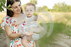 Happy young mother with cute baby son joyful exploring the world on field at sunny day