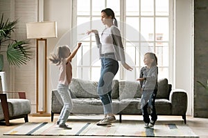 Happy young mother dancing with small children siblings.