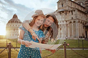 Happy young mother and daughter with map having excursion