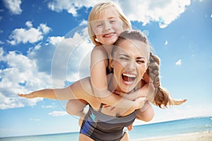 Happy young mother and daughter on seacoast rejoicing