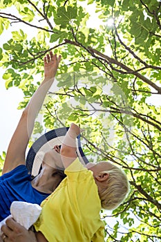 Happy young mother exploring nature with her baby boy showing hi