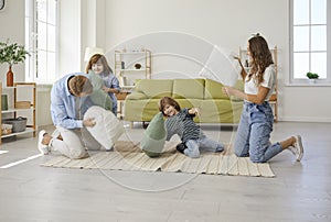 Happy young mother, father and children having a pillow fight in the living room