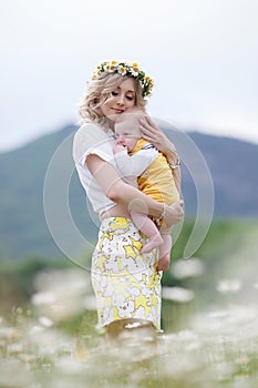 A happy young mother gently holds her newborn son in her arms