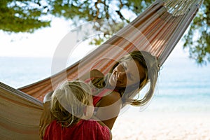 Happy young mother in a hammock with her toddler beside her