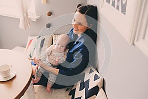 Happy young mother having breakfast in modern kitchen with her baby daughter