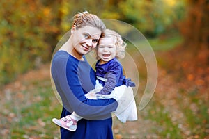 Happy young mother having fun cute toddler daughter, family portrait together. Pregnant woman with beautiful baby girl