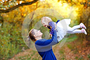 Happy young mother having fun cute toddler daughter, family portrait together. Woman with beautiful baby girl in nature