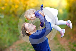 Happy young mother having fun cute toddler daughter, family portrait together. Woman with beautiful baby girl in nature