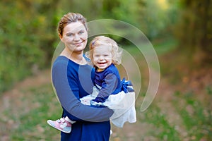 Happy young mother having fun cute toddler daughter, family portrait together. Woman with beautiful baby girl in nature