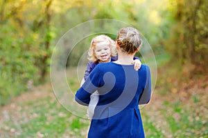 Happy young mother having fun cute toddler daughter, family portrait together. Woman with beautiful baby girl in nature